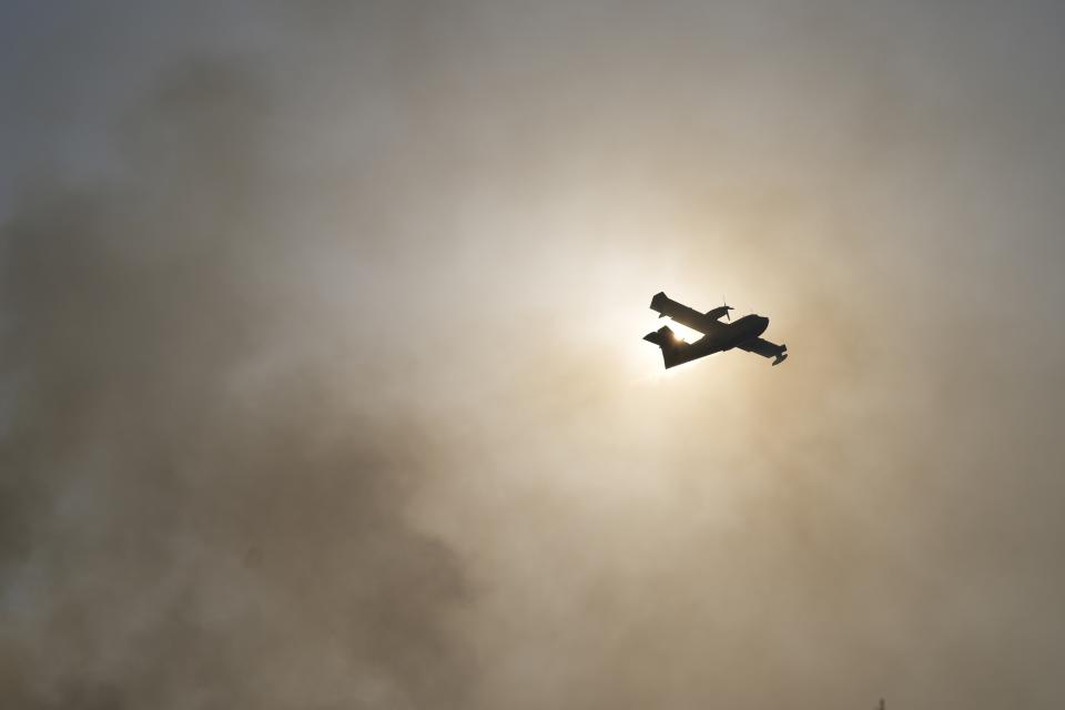 An aircraft operates in Varibobi area, northern Athens, Greece, Wednesday, Aug. 4, 2021. Firefighting planes were resuming operation at first light Wednesday to tackle a major forest fire on the northern outskirts of Athens which raced into residential areas the previous day, forcing thousands to flee their homes amid Greece's worst heatwave in decades. (AP Photo/Thanassis Stavrakis)