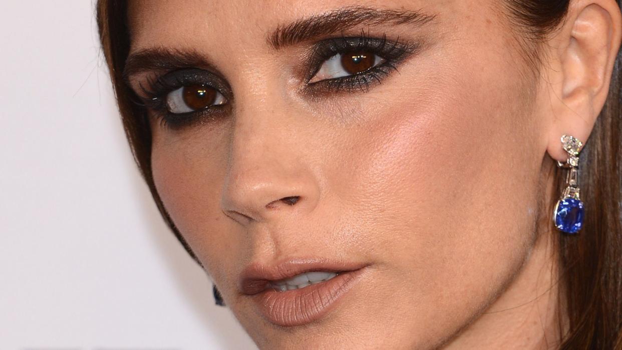 Victoria Beckham wearing black dress and sapphire earrings in close up picture