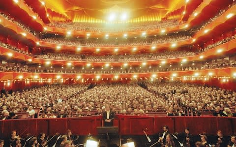 General view of the audience and the Metropolitan Opera Orchestra, with American artistic director and conductor James Levine - Credit: Getty