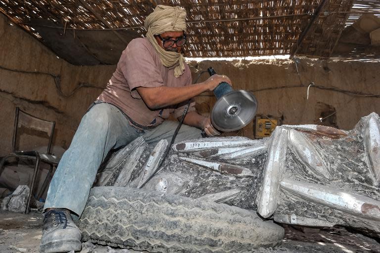 A sculptor cuts into a piece of rock filled with fossils in Erfoud, eastern Morocco on September 30, 2014