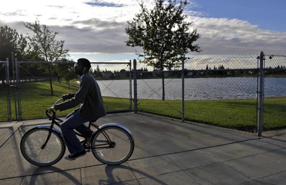 A cyclist rides past a recharge basin located along Shepherd Avenue in northeast Fresno in September 2014.