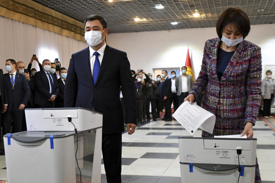 Kyrgyzstan's President Sadyr Japarov and his wife Aigul Asanbaeva cast their ballots at a polling station during the referendum in Bishkek, Kyrgyzstan, Sunday, April 11, 2021. Voters in Kyrgyzstan cast ballots Sunday on whether to approve a new constitution that would substantially increase the president's powers. The Sunday referendum comes three months after Sadyr Zhaparov was elected president, following the ouster of the previous president amid protests, the third time in 15 years that a leader of the Central Asian country had been driven from office in a popular uprising. (AP Photo/Vladimir Voronin)