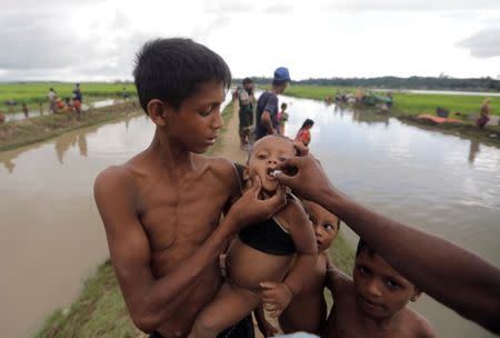 A Rohingya refugee boy who crossed the border from Myanmar a day before, gets an oral cholera vaccine, distributed by UNICEF workers as he waits to receive permission from the Bangladeshi army to continue his way to the refugee camps, in Palang Khali, near Cox's Bazar, Bangladesh October 17, 2017. REUTERS/ Zohra Bensemra