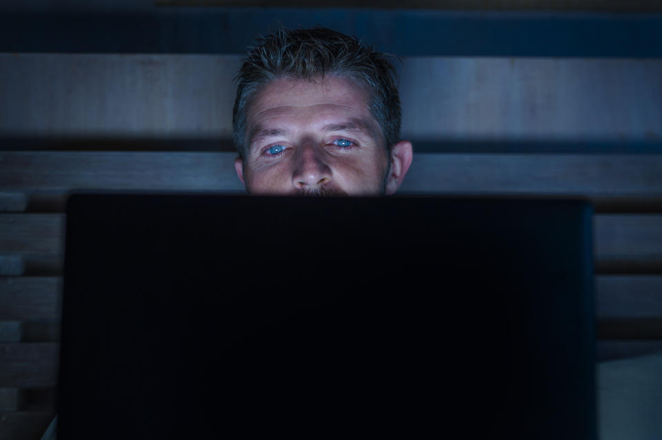 young attractive and relaxed internet addict man networking concentrated late at night on bed with laptop computer in social media addiction or workaholic businessman concept