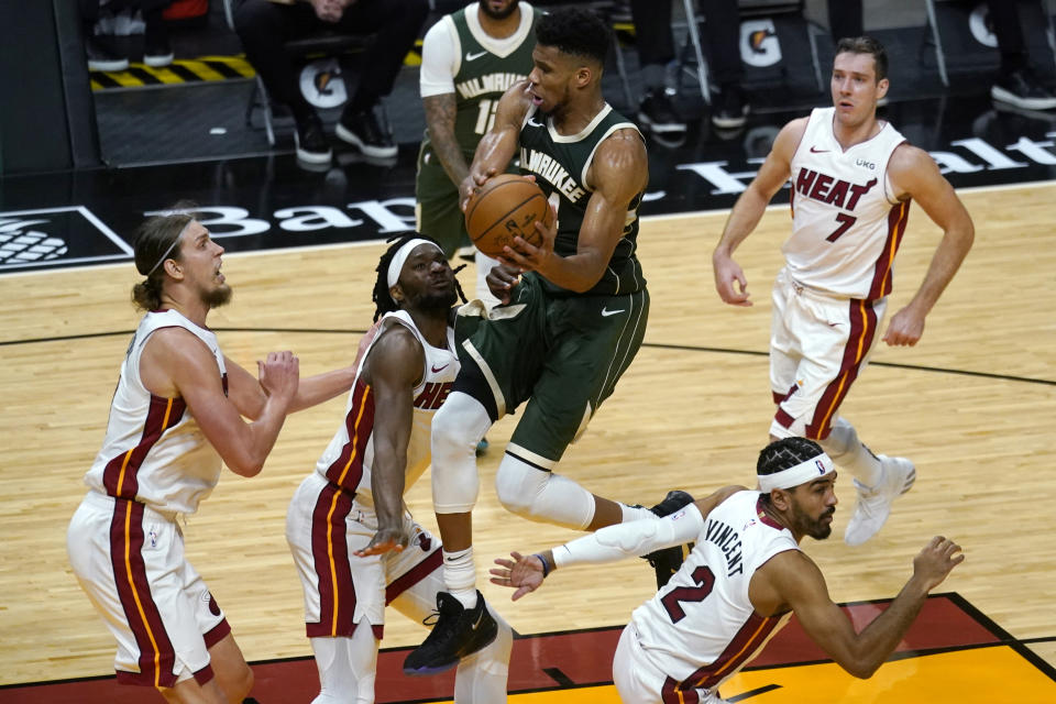 Milwaukee Bucks forward Giannis Antetokounmpo, center, drives to the basket as Miami Heat forward Kelly Olynyk, left, forward Precious Achiuwa, second from left, and guard Gabe Vincent (2) defend during the second half of an NBA basketball game Wednesday, Dec. 30, 2020, in Miami. (AP Photo/Lynne Sladky)