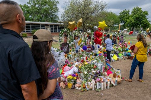 People visit a memorial to the 19 children and two adults killed during the mass shooting in Uvalde, Texas.