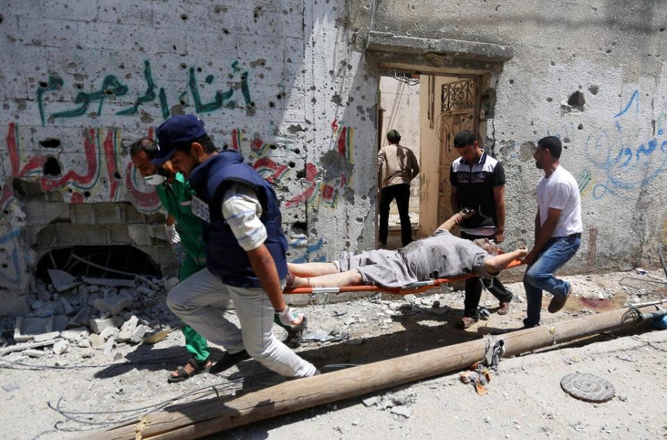 Palestinian medics carry the body of a man killed in Gaza City's Shijaiyah neighborhood that came under fire as Israel widened its ground offensive against Hamas in the northern Gaza Strip on Sunday, July 20, 2014