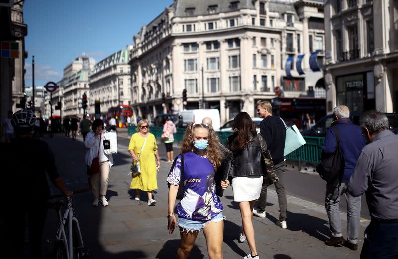 Pedestrians, some wearing protective face masks, walk along Regent Street, amid the coronavirus disease (COVID-19) outbreak, in London