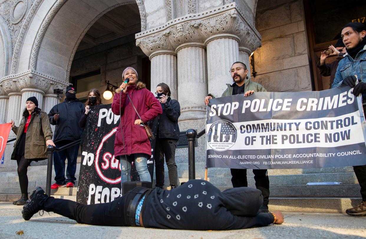 Adelana Akindes, a member of Students for a Democratic Society, from Kenosha, delivers a speech Saturday outside the Federal Courthouse in Milwaukee during a rally protesting the not guilty verdicts in the Kyle Rittenhouse trial. Sharaka Berry, event planner of Our Wisconsin Revolution, lies on the ground wearing a hoodie that symbolizes the gunshots that struck the back of Jacob Blake, who was shot by a Kenosha police officer in August 2020.