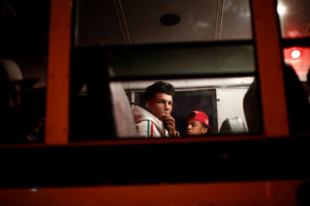 A migrant, part of a caravan of thousands traveling from Central America en route to the United States, eats food in a bus while during a stop to wait for another bus to undergo repairs, on its way to Mexicali, on a shoulder of a highway in Sonoyta, Mexico November 17, 2018. REUTERS/Kim Kyung-Hoon