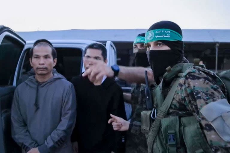 Una imagen de un vídeo distribuido por la Oficina de Prensa de Hamás muestra a miembros de sus Brigadas Al-Qassam entregando rehenes a funcionarios del Comité Internacional de la Cruz Roja en Gaza el 24 de noviembre de 2023, antes de su traslado a Israel.