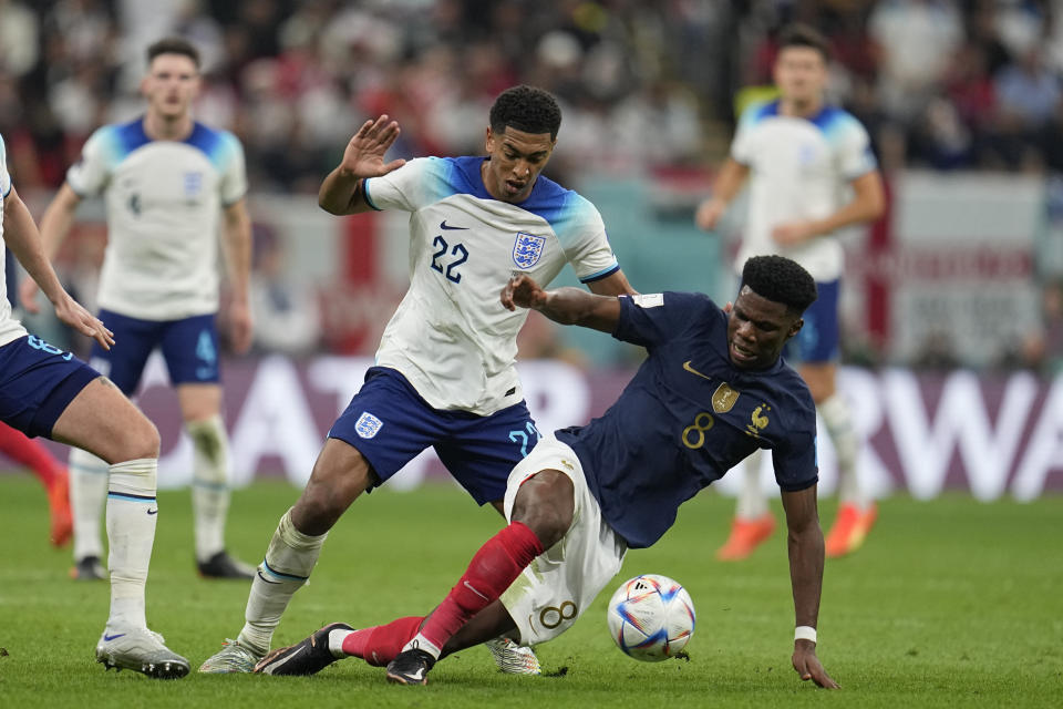 El francés Aurelien Tchouameni disputa el balón con el inglés Jude Bellingham durante el partido por los cuartos de final del Mundial, el sábado 10 de diciembre de 2022, en Jor, Qatar. (AP Foto/Abbie Parr)