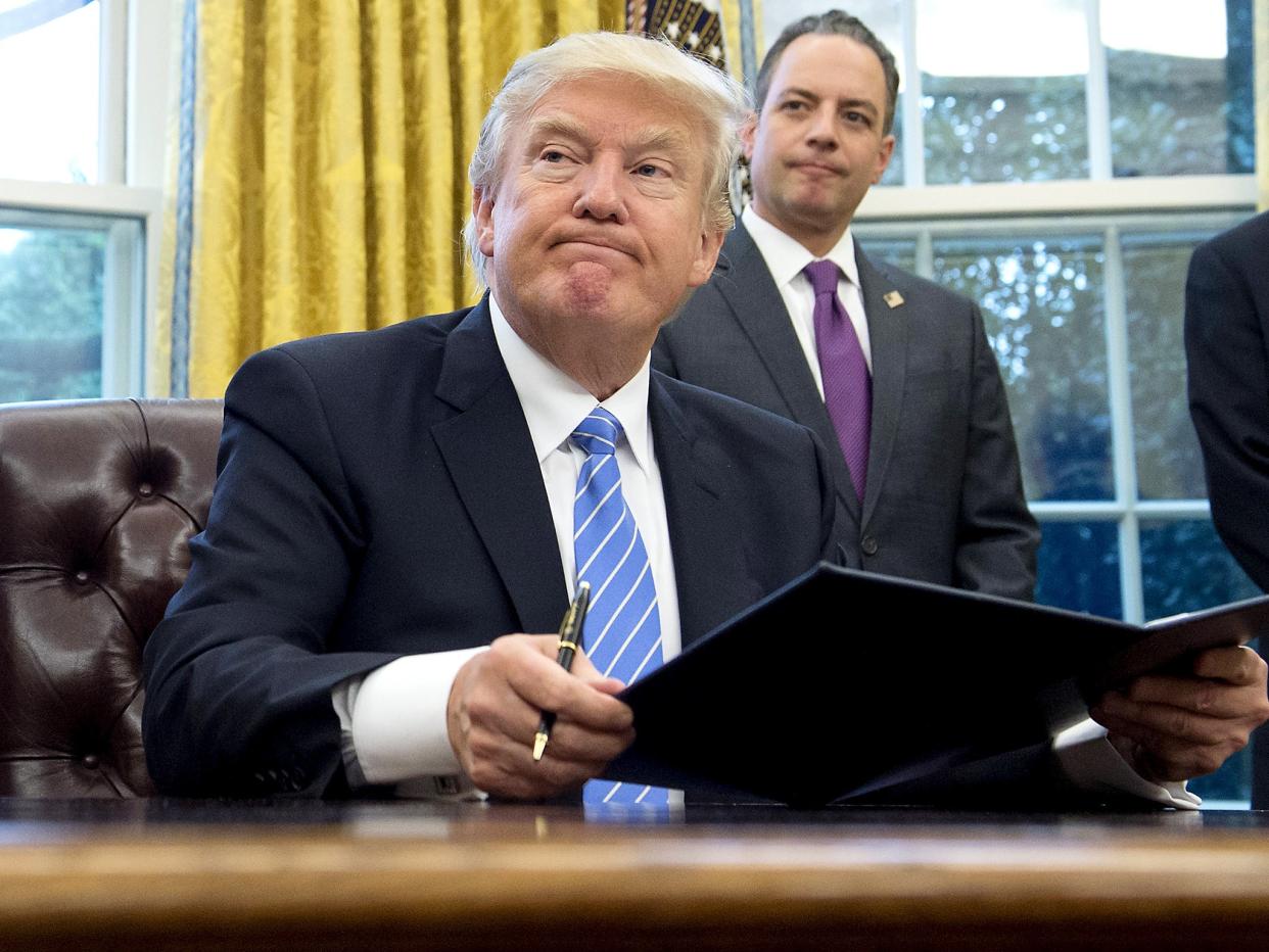 US President Donald Trump signs an executive order as Chief of Staff Reince Priebus looks on in the Oval Office of the White House: Getty Images
