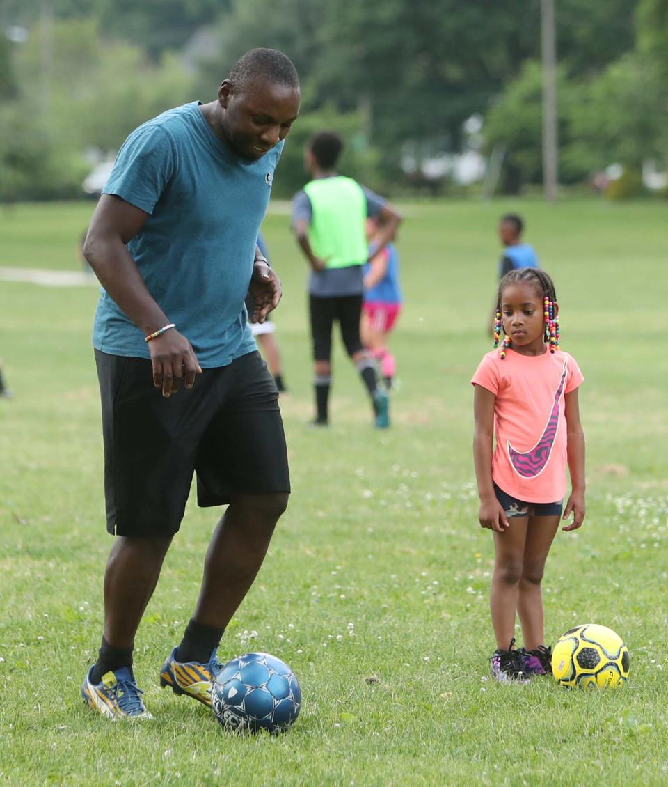 Bailey Bonds, 6, right, watches the fancy footwork of soccer coach  Chidozie Martins during the 15th annual free summer soccer camp put on by the Akron Inner City Soccer Club at Hardesty Park in Akron on Monday.
