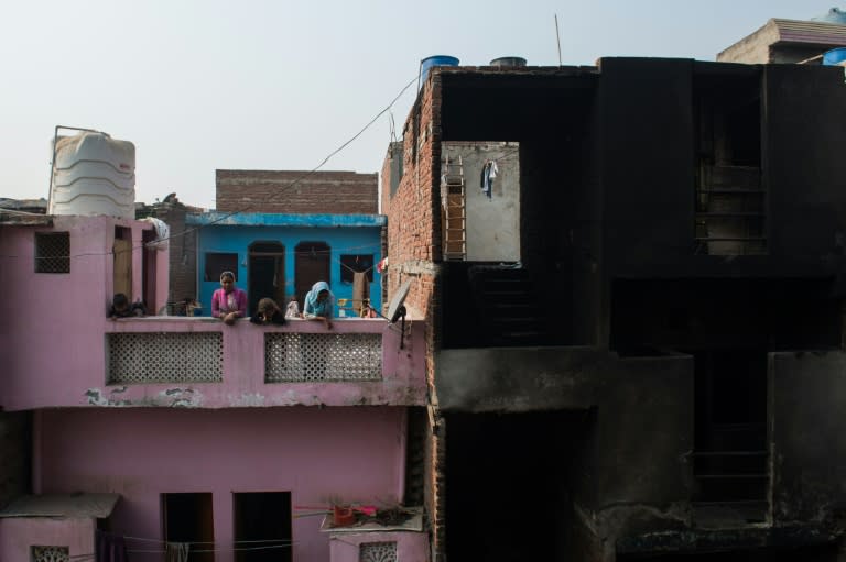 Neighbours stand on an adjacent roof near a gutted workshop in Ghaziabad, some 20 km east of New Delhi, on November 11, 2016