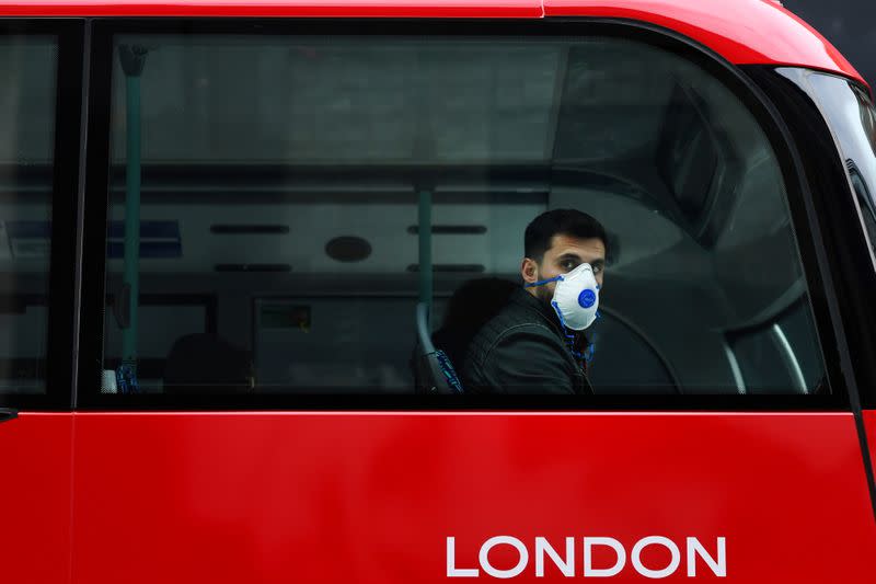 A man wears a mask while sitting on a bus in London