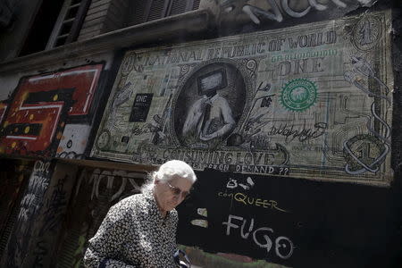 A woman walks past graffiti illustrating a modified dollar banknote in Athens, June 3, 2015. REUTERS/Alkis Konstantinidis