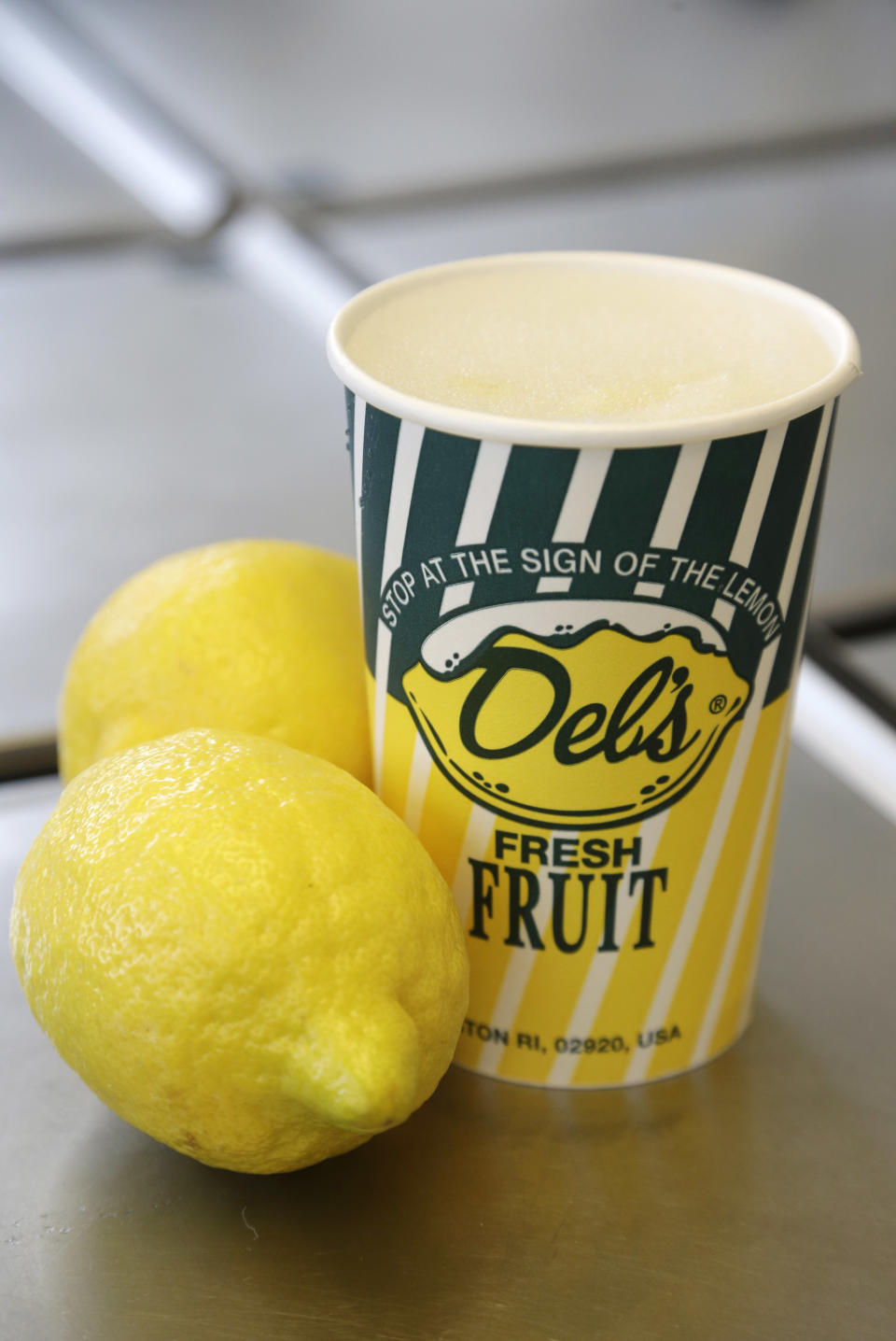 This April 30, 2014 photo shows fresh lemons near a frozen lemonade drink at a Del's Lemonade location in Cranston, R.I. The lemony slush, made of water, sugar, lemon juice and chunks of rind, has become a cultural icon in the state. It's not unusual to see the trucks or carts at wedding receptions, birthday parties, bar mitzvahs, and troop deployments and homecomings. (AP Photo/Steven Senne)