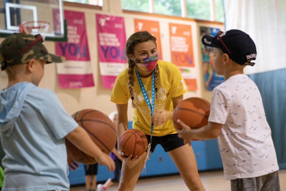 A counselor wearing a protective face mask plays with children as summer camps reopen amid the spread of coronavirus disease (COVID-19) at Carls Family YMCA summer camp in Milford, Michigan, U.S., June 23, 2020.  REUTERS/Emily Elconin