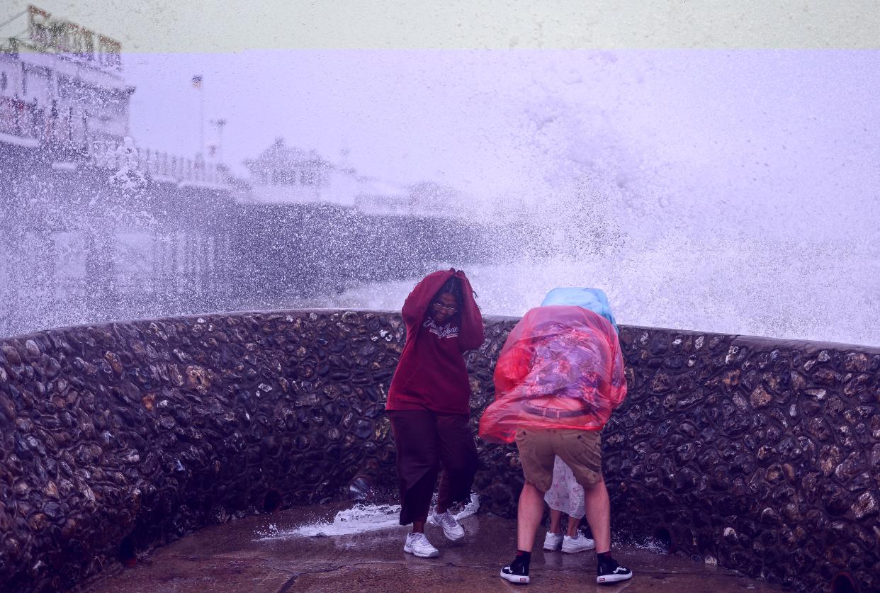 People react as a wave hits a seawall next to the Palace Pier in Brighton, southern England on August 5, 2023, as Storm Antoni brings rain and high winds to the UK. (AFP via Getty Images)