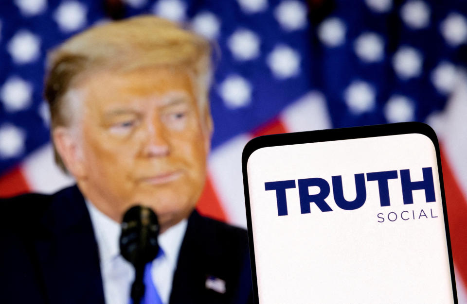 FILE PHOTO: The Truth social network logo is seen on a smartphone in front of a display of former U.S. President Donald Trump in this picture illustration taken February 21, 2022. REUTERS/Dado Ruvic/Illustration/File Photo