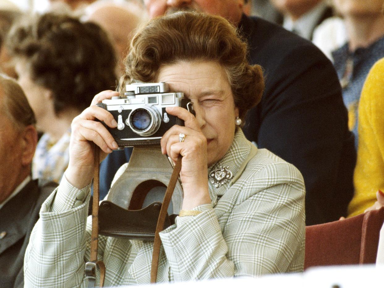 WINDSOR, UNITED KINGDOM - Queen Elizabeth II at The Windsor Horse Show, 16th May 1982. She is taking pictures of her husband with her Leica M3 camera. She is wearing her engagement ring and the Cullinan V diamond heart brooch.