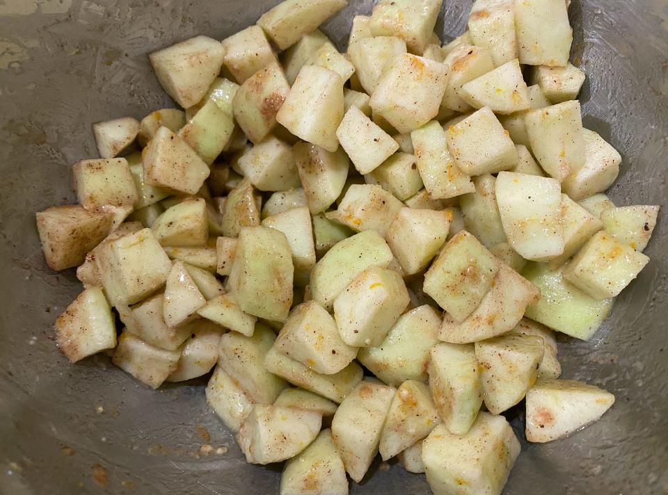 chopped apples in a bowl with cinnamon, butter, and sugar