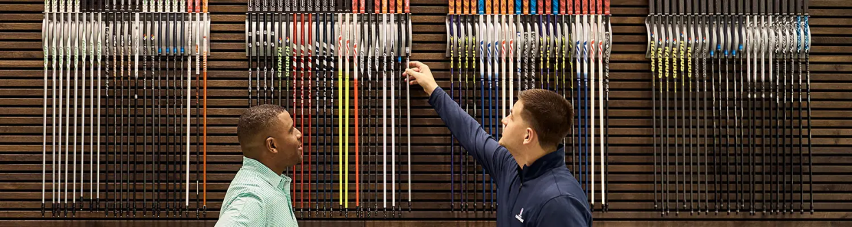  two men selecting golf clubs from the pga tour superstore 