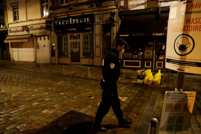 A police officer wearing a face mask patrols in the streets of Lille during the start of the late-night curfew due to restrictions against the spread of the coronavirus disease (COVID-19), in Lille