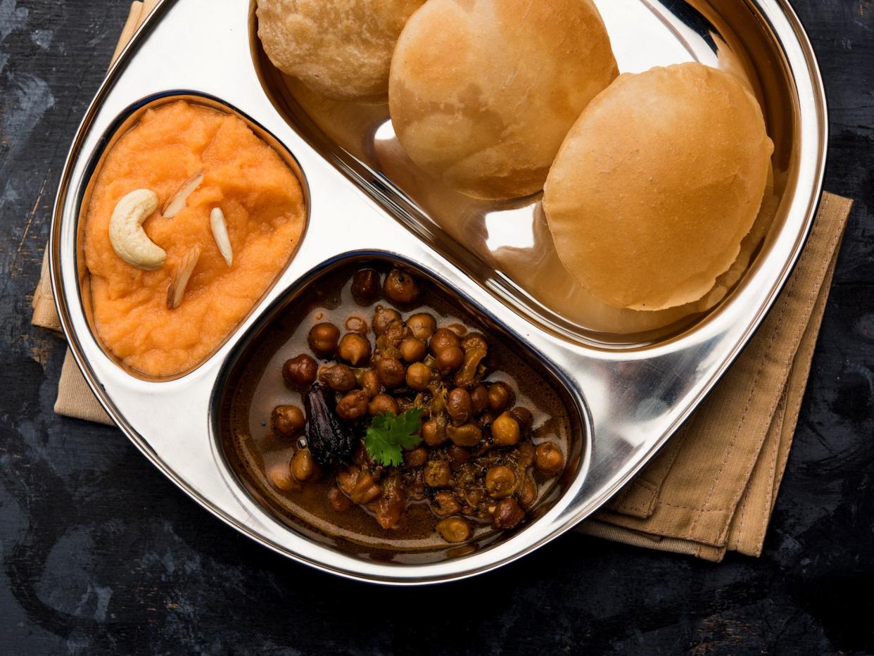 Suji / Sooji Halwa Puri or Shira Poori with black chana masala breakfast, served in a plate and bowl.