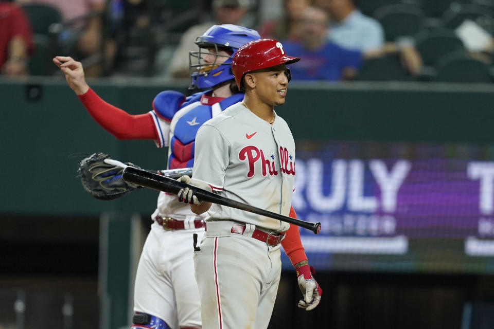 Philadelphia Phillies' Yairo Munoz looks back at the umpire after being called out on a dead ball strike out in the seventh inning of a baseball game as Texas Rangers catcher Jonah Heim, rear, stands by the plate, Tuesday, June 21, 2022, in Arlington, Texas. (AP Photo/Tony Gutierrez)