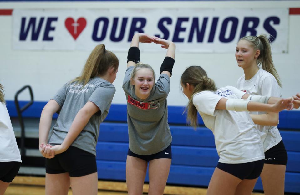 Anna Powell, center, stretches with teammates as the Sacred Heart volleyball team practices at the school gymnasium in Louisville, Ky. on Nov. 4, 2021.  They are preparing for the state tournament.