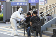 A health official wearing protective gear gives surveys to people waiting for the COVID-19 test at a public health center in Goyang, South Korea, Thursday, May 28, 2020. South Korea on Thursday reported its biggest jump in coronavirus cases in more than 50 days, a setback that could erase some of the hard-won gains that have made it a model for the rest of the world. (AP Photo/Ahn Young-joon)