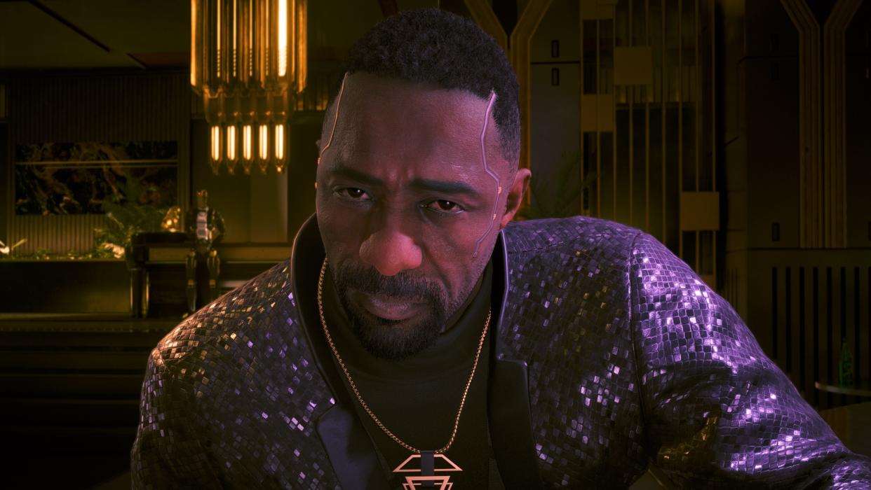  Idris Elba in Cyberpunk in snazzy jacket leaning forward. 