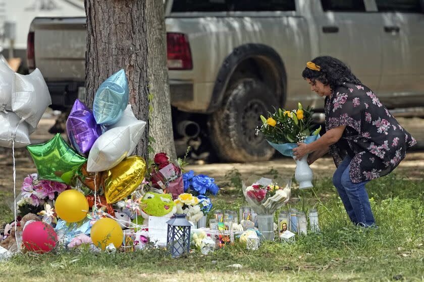 Maria Rodriguez places flowers Tuesday, May 2, 2023, outside the home where a mass shooting occurred Friday, in Cleveland, Texas. The search for the suspected gunman who allegedly shot five of his neighbors, including a child, after they asked him to stop firing off rounds in his yard stretched into a fourth day Tuesday. (AP Photo/David J. Phillip)