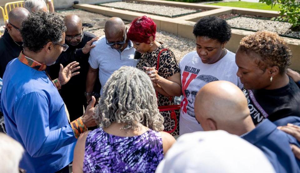 Emanuel Cleaver III, senior pastor at St. James United Methodist Church, prays for Cameron Lamb’s stepfather, Aquil Bey, left, mother Laurie Bey and sisters Shelice Sheppard and Vanessa Gray on Tuesday, June 13, 2023, in Kansas City. Faith leaders held a press conference in reaction to the news that Gov. Mike Parson is considering a pardon for KCPD detective Eric DeValkenaere, who was convicted in 2021 of second-degree involuntary manslaughter and armed criminal action in the fatal shooting of Lamb.