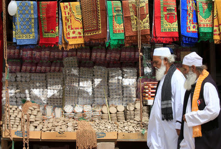 Men walk past a shop selling "turba", a piece of stone or molded clay made of local soil, in Najaf, Iraq April 3, 2018. REUTERS/Alaa Al-Marjani