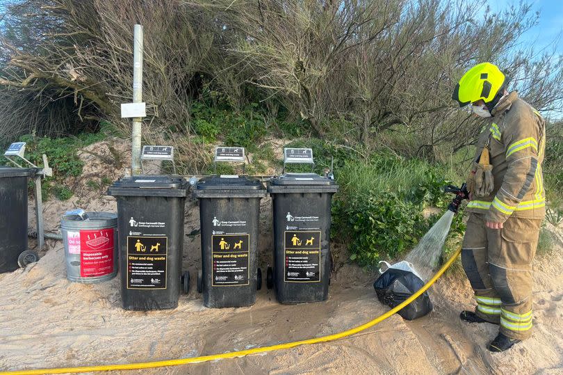 Firefighter extinguishing an accidental beach bin fire