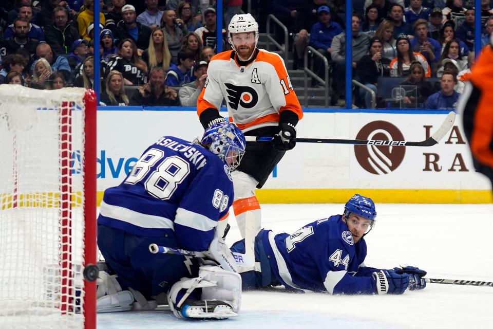 Philadelphia Flyers center Sean Couturier (14) watches his shot o wide of Tampa Bay Lightning goaltender Andrei Vasilevskiy (88) and defenseman Jan Rutta (44) during the first period of an NHL hockey game Tuesday, Nov. 23, 2021, in Tampa, Fla. (AP Photo/Chris O'Meara)