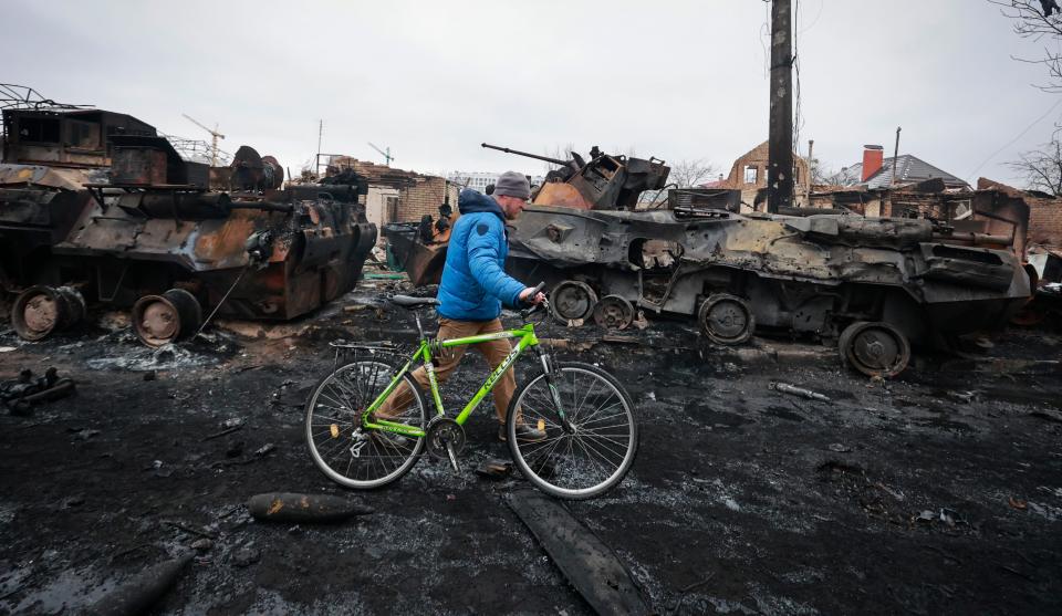 A man passes the remains of Russian military vehicles in Bucha, near the Ukrainian capital of Kyiv, on March 1.