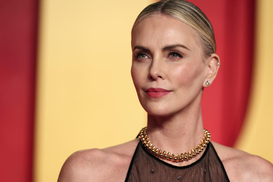 Charlize Theron on the red carpet wearing a halter dress with a beaded neckline