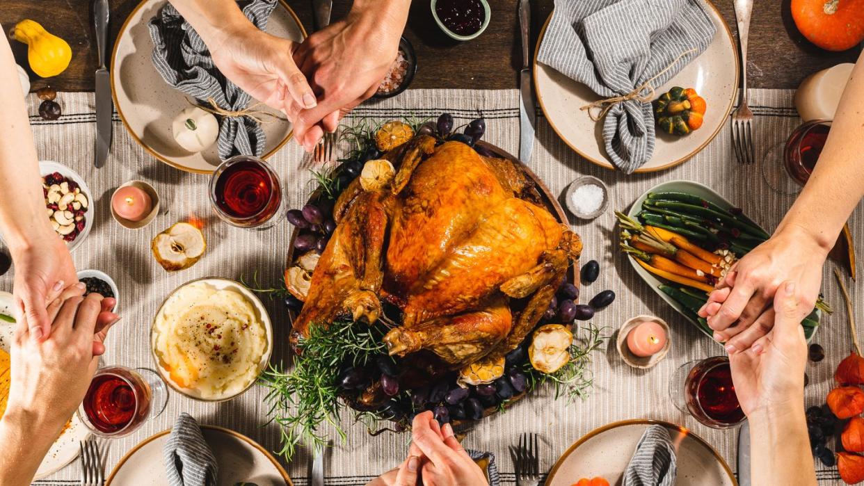 family holding hands and praying during thanksgiving dinner