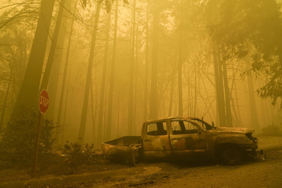 A burned out vehicle is left in front of a fire- ravaged residence as smoke from the CZU August Lightning Complex Fire fills the sky Saturday, Aug. 22, 2020, in Boulder Creek, Calif. (AP Photo/Marcio Jose Sanchez)
