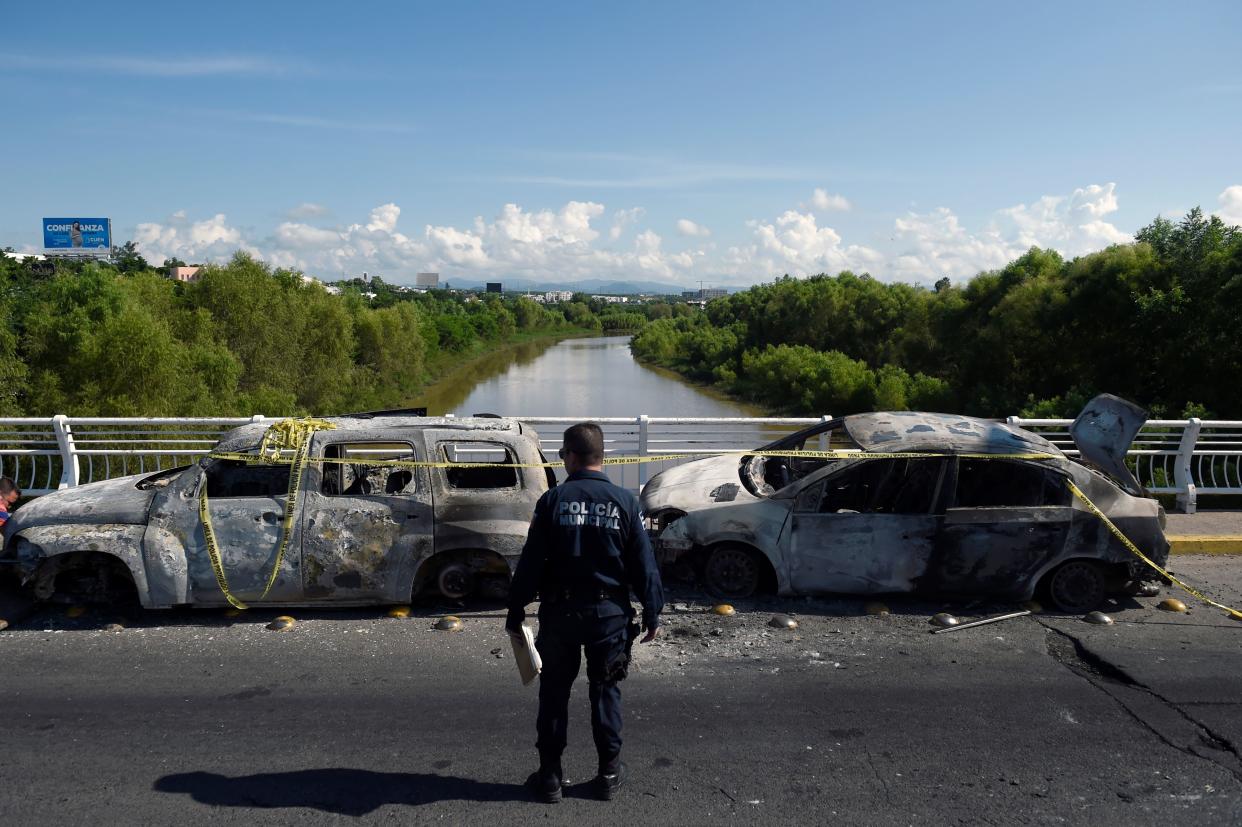 A policeman stands next to burnt vehicles after heavily armed gunmen waged an all-out battle against Mexican security forces in Culiacan, Sinaloa state, Mexico, on October 18, 2019. - Mexico's president faced a firestorm of criticism Friday as his security forces confirmed they arrested kingpin Joaquin "El Chapo" Guzman's son, then released him when his cartel responded with an all-out gun battle. (Photo by ALFREDO ESTRELLA / AFP) (Photo by ALFREDO ESTRELLA/AFP via Getty Images)