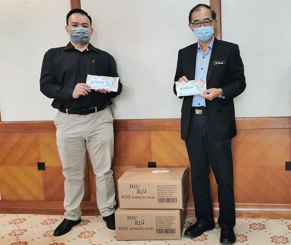 BZU BZU's regional sales director Edmund Chin (left) and deputy Education Minister Datuk Mah Hang Soon (right) with the face masks for students. — Picture courtesy of BZUBZU Malaysia