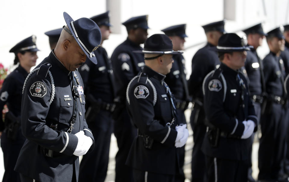 An police officer lowers his head as he waits for the procession for Ventura County Sheriff's Sgt. Ron Helus at the Calvary Community Church Thursday, Nov. 15, 2018, in Westlake Village, Calif. Helus was fatally shot while responding to a mass shooting at a country music bar in Southern California. (AP Photo/Marcio Jose Sanchez, Pool)