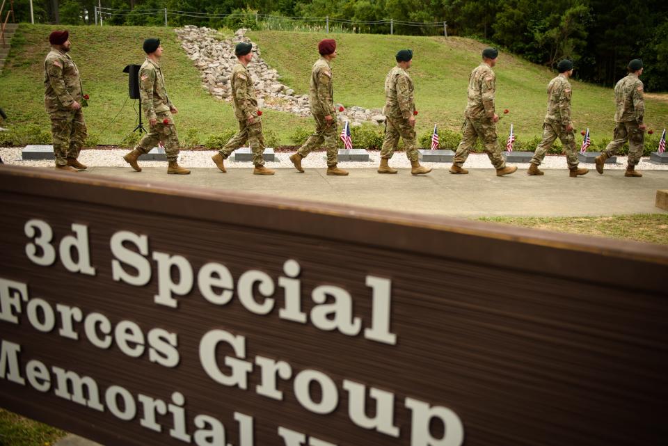 Soldiers hold roses as they march out to place them on the memorial stones during 3rd Special Forces Group's memorial ceremony, which honors the group's soldiers killed in action.