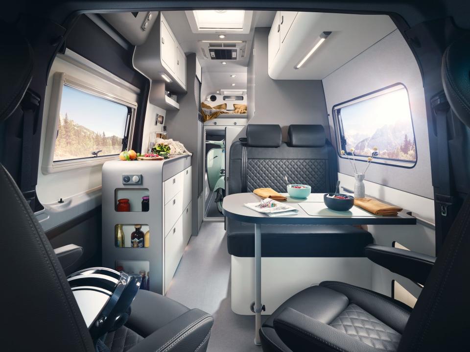 A dining table in a camper van. The driver and passenger seats have swiveled to face the table.