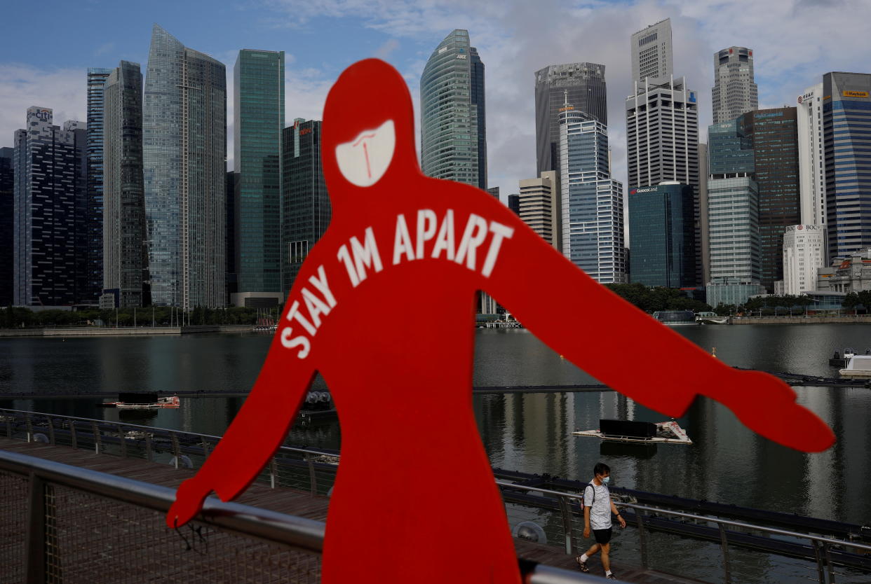 A man wearing a face mask passes a sign put up to encourage social distancing during the coronavirus disease (COVID-19) outbreak, at Marina Bay in Singapore, September 22, 2021. REUTERS/Edgar Su