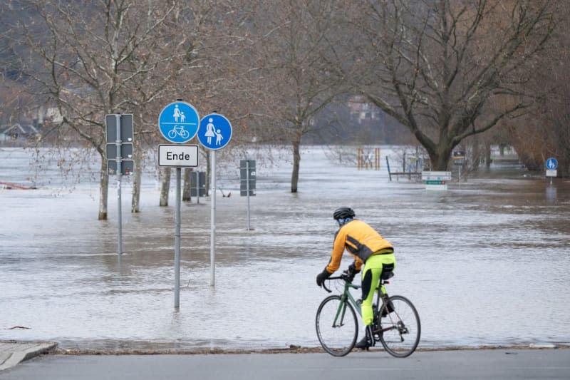 A cyclist stands on a flooded road after the flood of the Elbe River. The flood situation in Saxony remains tense, especially along the Elbe. Sebastian Kahnert/dpa